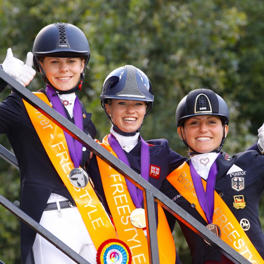 It’s a big thumbs up from Jil-Marielle Becks GER (silver), Charlotte Fry GBR (gold) and Lisa Maria Klossinger GER (bronze) after stepping off the Freestyle podium at the FEI European Dressage Championships U25 2018 in Exloo, The Netherlands today. FEI/Leanjo de Koster, DigiShots