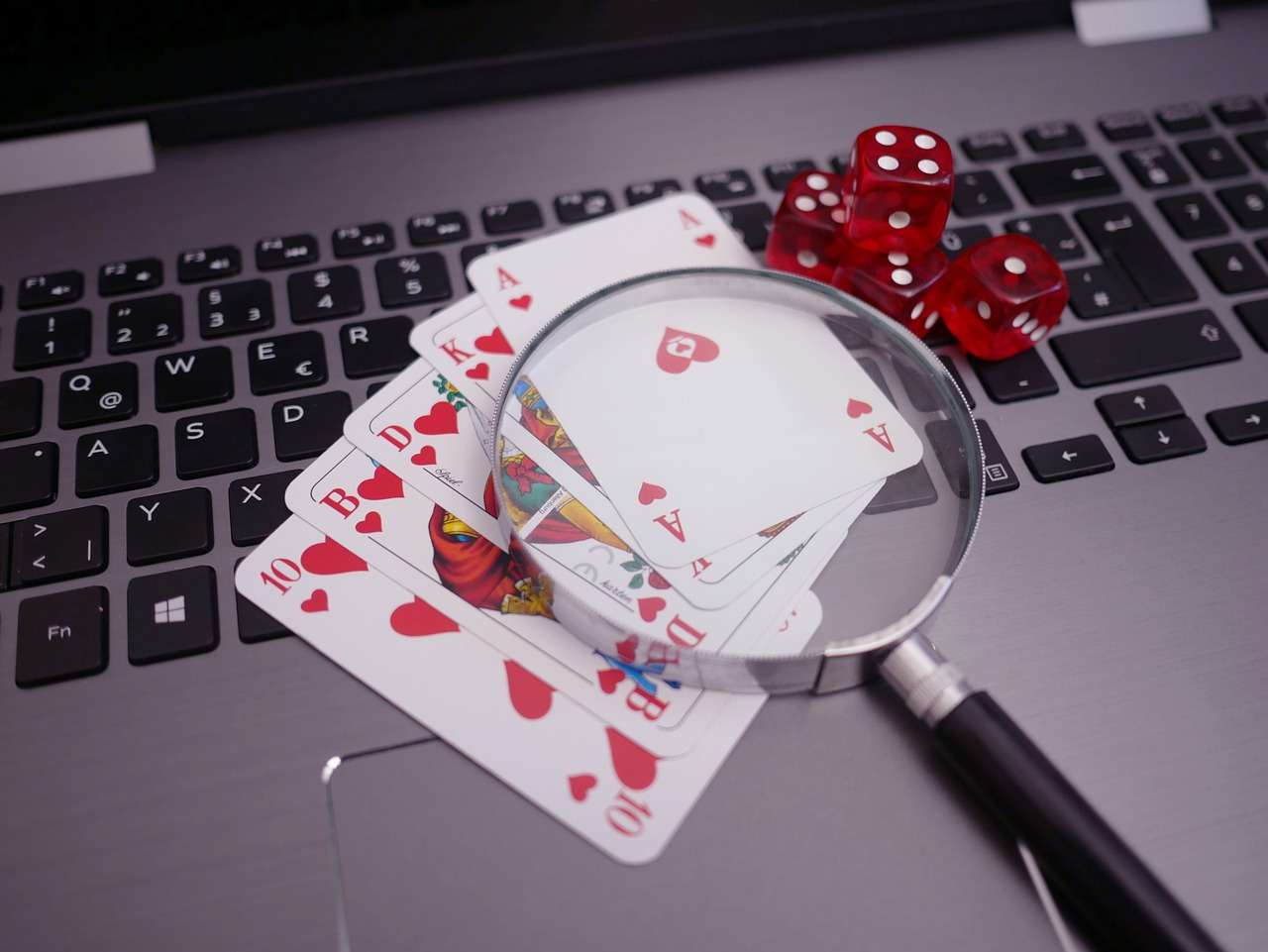 How to Find and Claim the Best Online Casino Promotions and Offers in the UK cards and dice on laptop keyboard with a magnifying glass