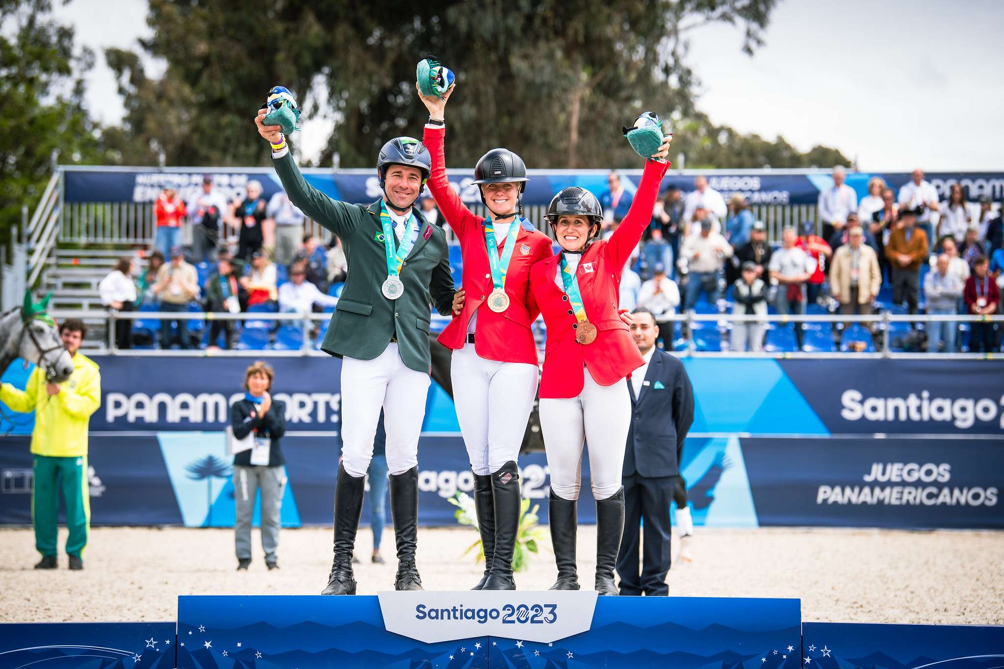 Marcio CARVALHO JORGE (BRA) bronze, Caroline PAMUKCU (USA) gold and Lindsay TRAISNEL (CAN) silver on the podium during show jumping in eventing at the Pan American Games Santiago, Chile 2023 Copyright ©FEI/Shannon Brinkman