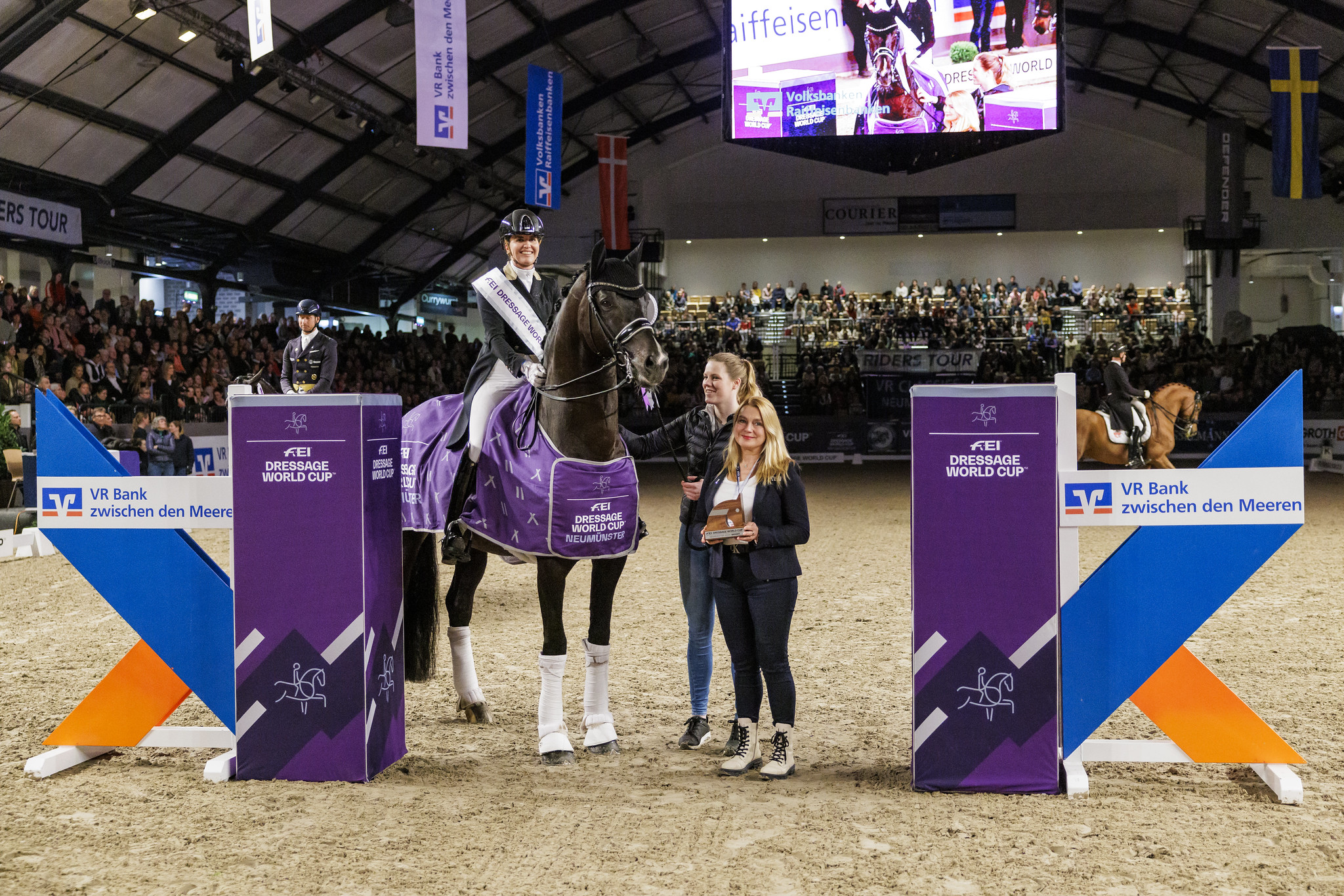 Emmelie Scholtens (NED) and Indian Rock - winners of the FEI Dressage World Cup™ 2024 - Neumünster (GER) with Anna Milne (FEI) during the prize ceremony. Copyright © FEI/www.sportfotos-lafrentz.de/Stefan Lafrentz