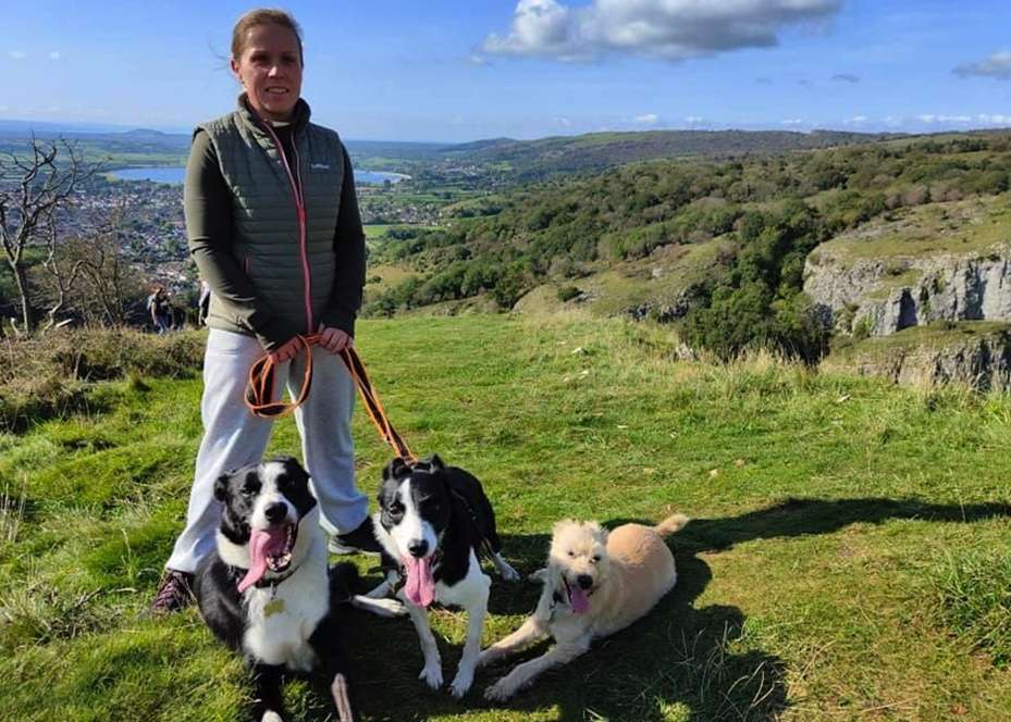 Katie Nicols, 45 stood on a hill with her three dogs