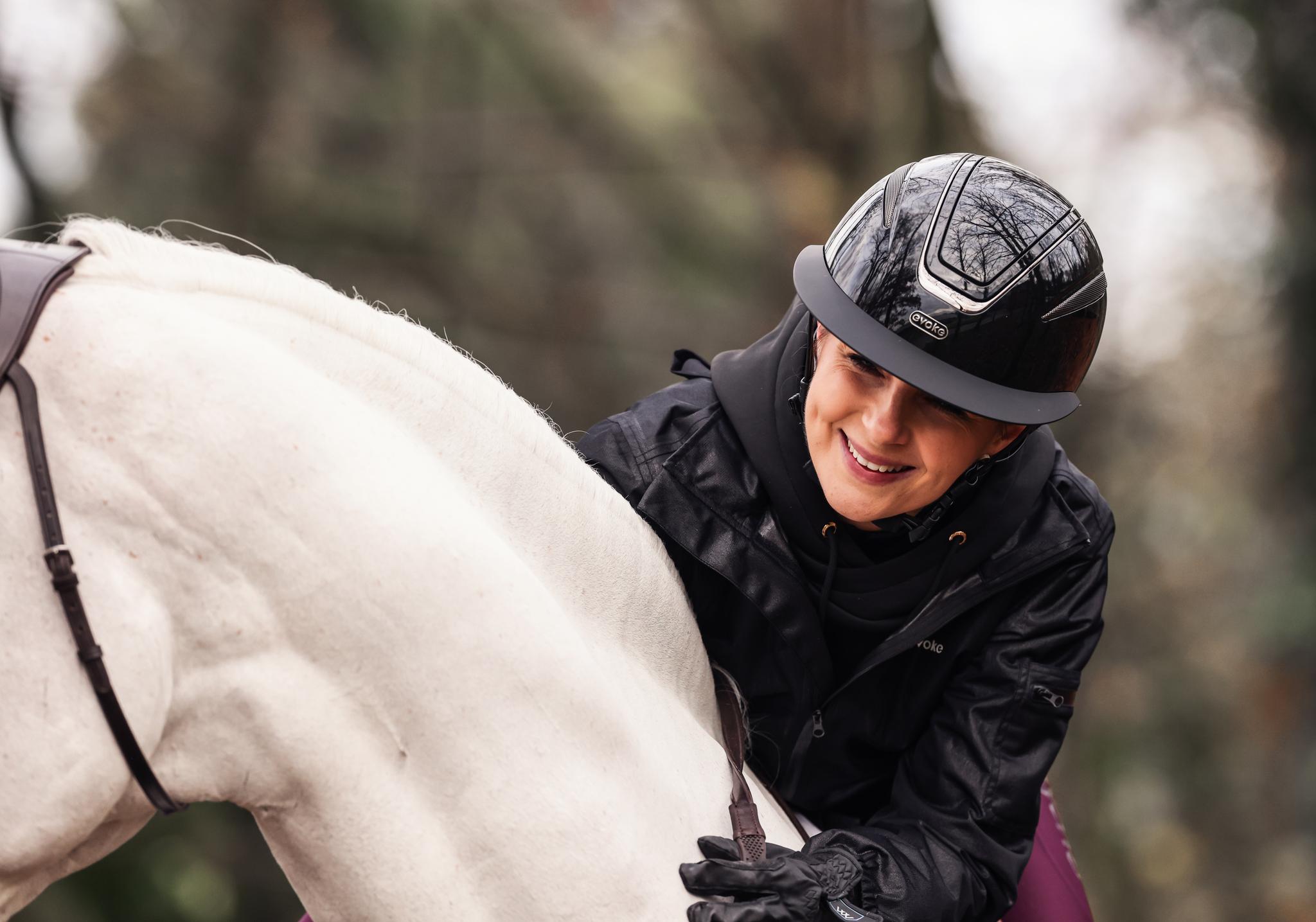 a yound lady on a horse wearing an evoke helmet