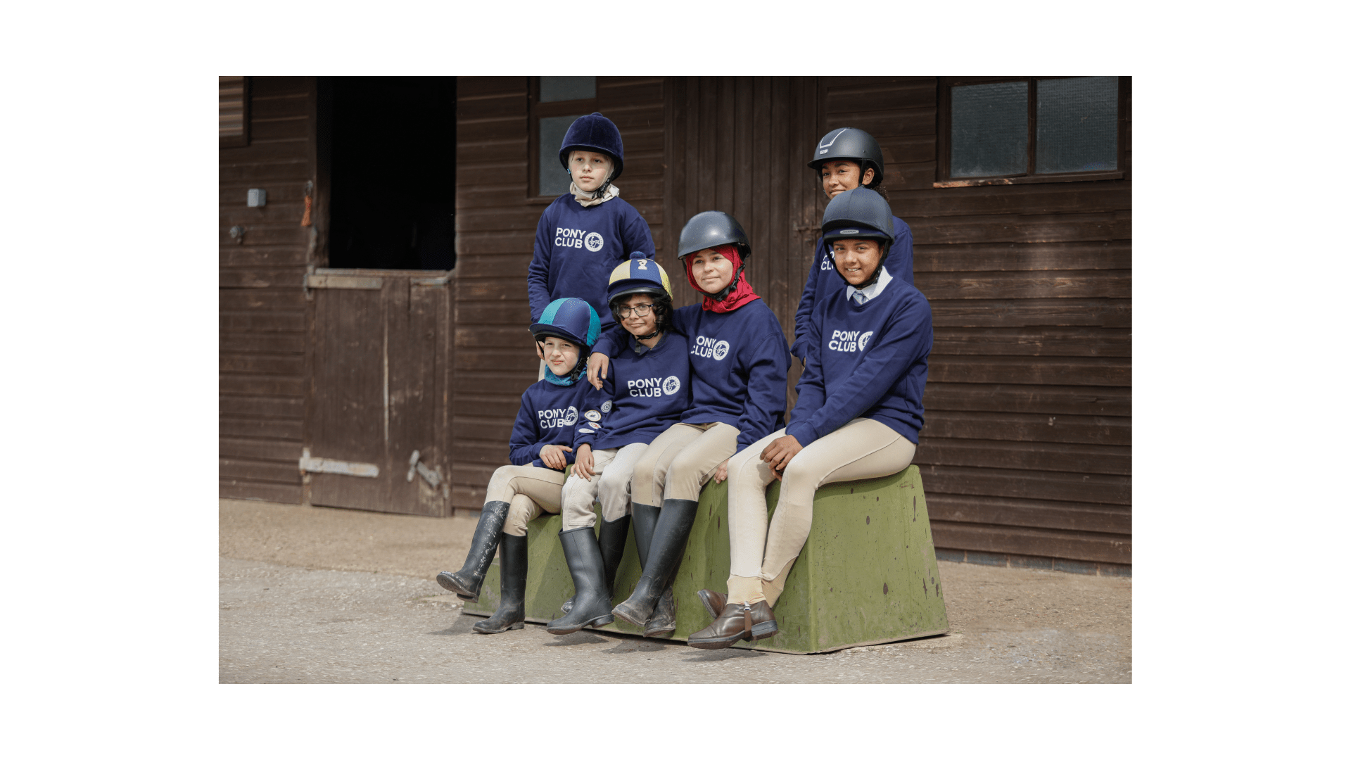 A group of pony club children sat on a large green mountain block